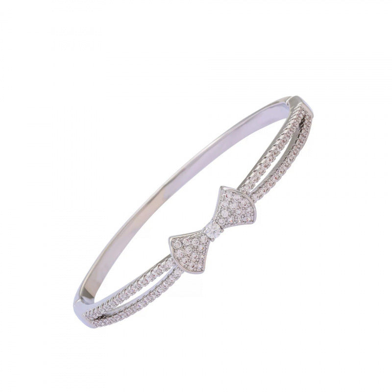 Bow Tie Bangle In Copper With Electroplated Gold Plating Featuring Rhinestone Inlay