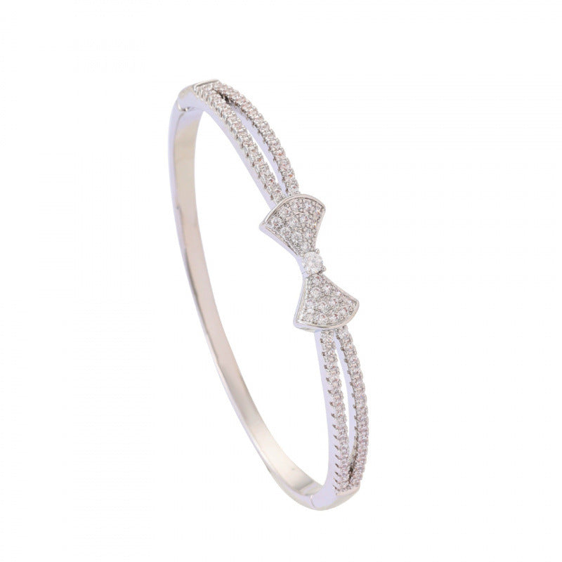 Bow Tie Bangle In Copper With Electroplated Gold Plating Featuring Rhinestone Inlay