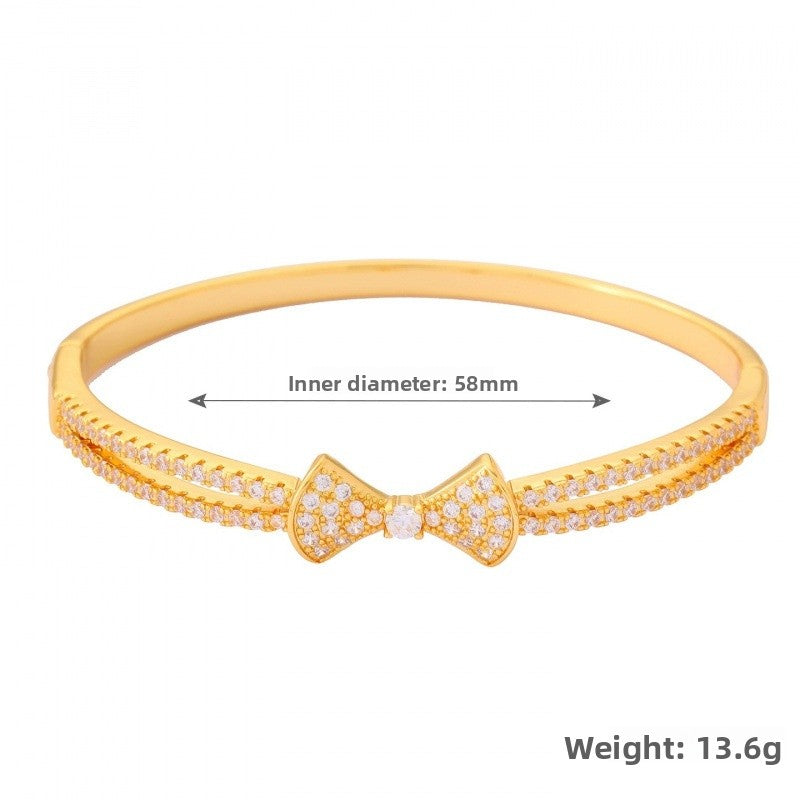Bow Tie Bangle In Copper With Electroplated Gold Plating Featuring Rhinestone Inlay